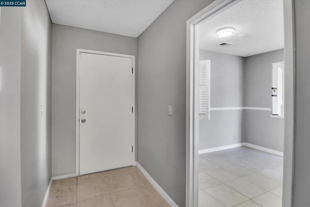 hallway with light tile patterned flooring and a textured ceiling