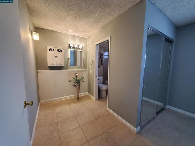 bathroom featuring tile patterned flooring, a textured ceiling, and toilet