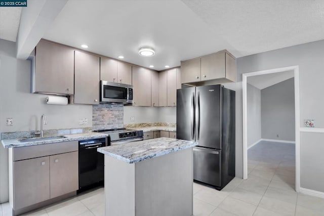 kitchen featuring sink, backsplash, a center island, light stone counters, and stainless steel appliances