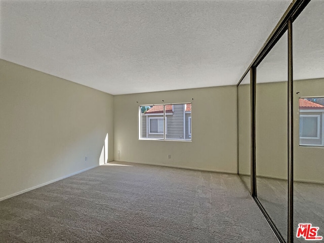 carpeted spare room with a textured ceiling