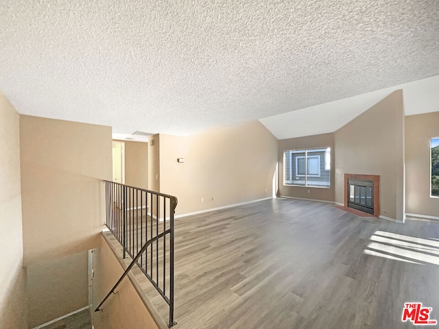 unfurnished living room with hardwood / wood-style flooring, lofted ceiling, and a textured ceiling