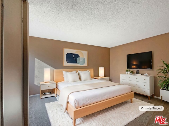 bedroom featuring a textured ceiling and dark carpet