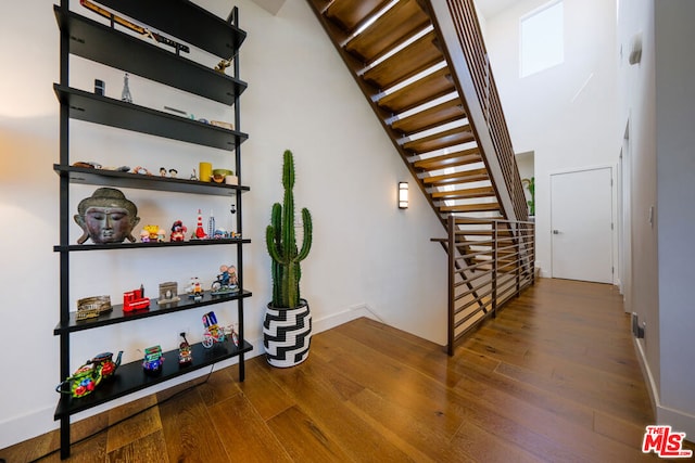 staircase with hardwood / wood-style floors and a towering ceiling