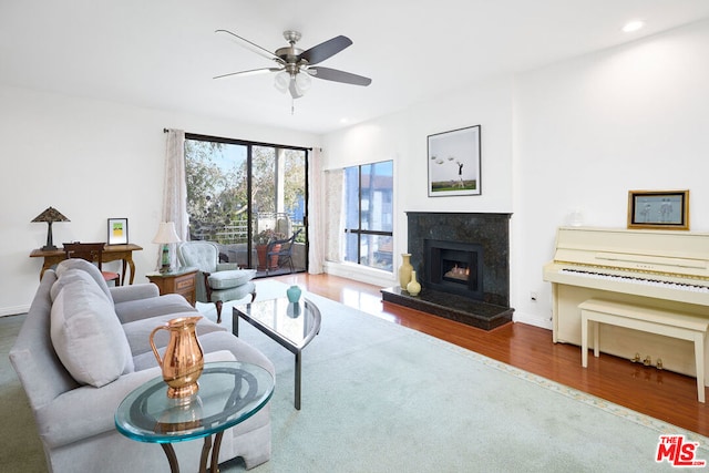 living room with ceiling fan, wood-type flooring, and a high end fireplace