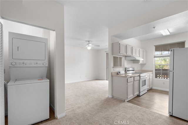 kitchen featuring stainless steel range with electric cooktop, stacked washer / dryer, white cabinets, light colored carpet, and white fridge