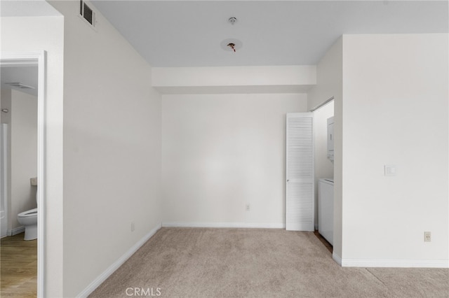 unfurnished bedroom featuring light colored carpet, connected bathroom, and a closet