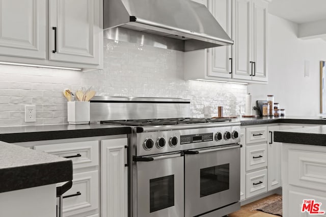 kitchen featuring tasteful backsplash, white cabinets, and range with two ovens