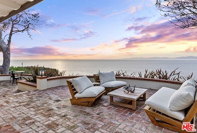 patio terrace at dusk featuring a water view