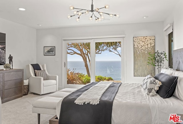 bedroom with a water view, an inviting chandelier, light carpet, and access to outside