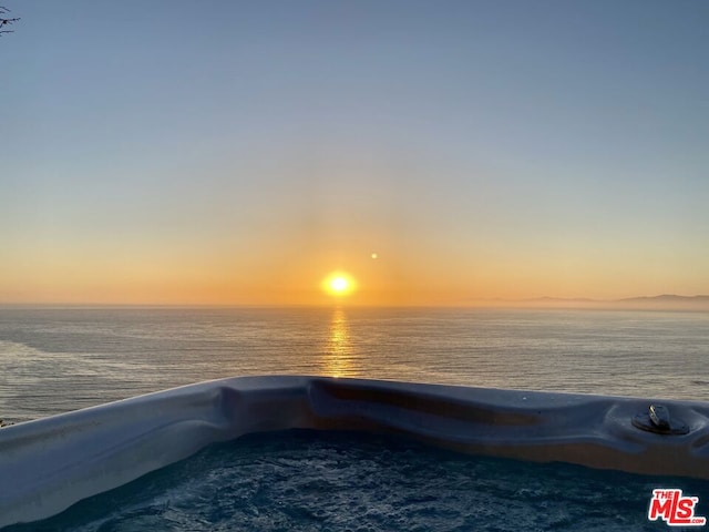 pool at dusk featuring a water view