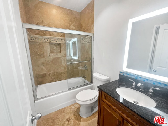 full bathroom featuring vanity, shower / bath combination with glass door, and toilet