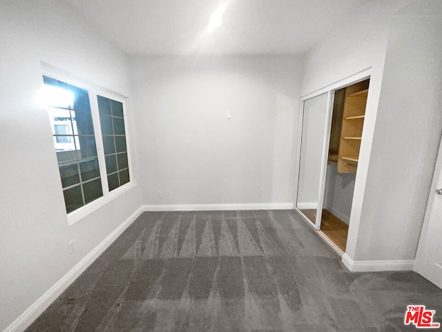 unfurnished bedroom featuring a closet and dark colored carpet