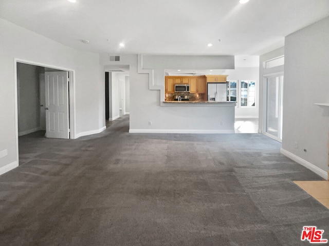 unfurnished living room with dark colored carpet