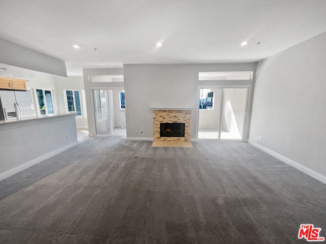 unfurnished living room featuring a tiled fireplace and carpet flooring