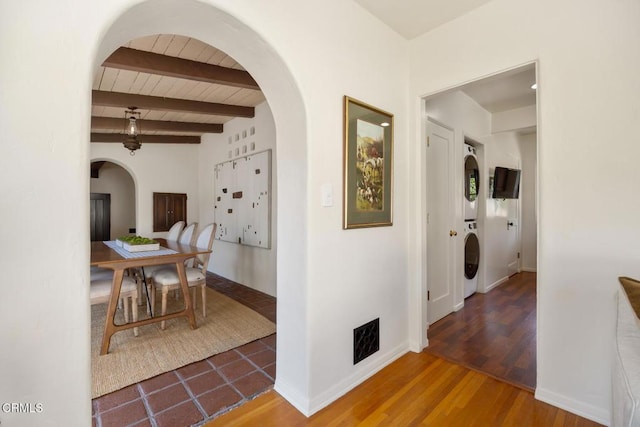 hall featuring stacked washer / drying machine, beam ceiling, and hardwood / wood-style floors