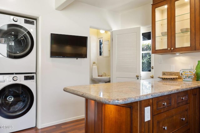 clothes washing area with stacked washer and clothes dryer and dark hardwood / wood-style flooring