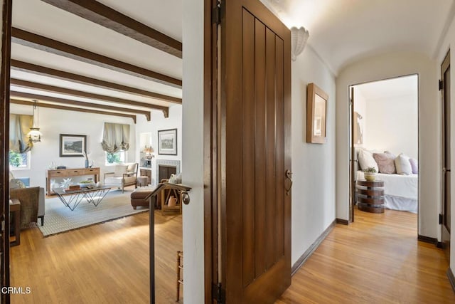 hallway featuring beamed ceiling and light hardwood / wood-style flooring