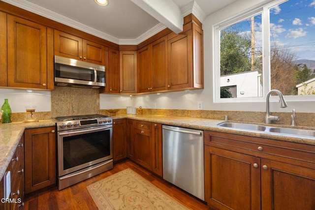 kitchen with sink, hardwood / wood-style flooring, appliances with stainless steel finishes, backsplash, and light stone countertops