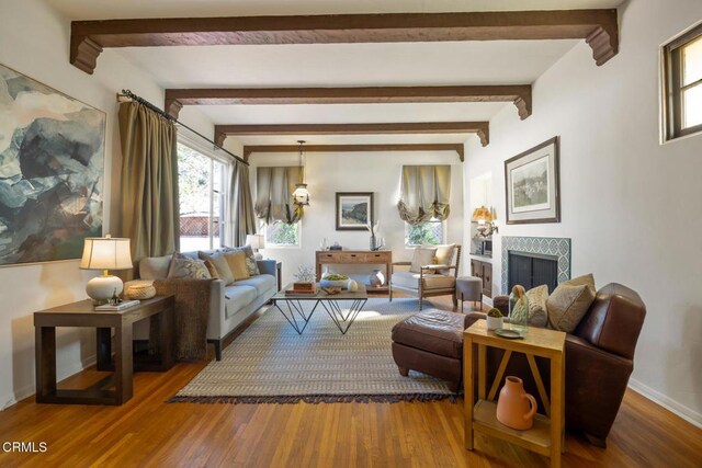 living room featuring beam ceiling, a fireplace, and wood-type flooring