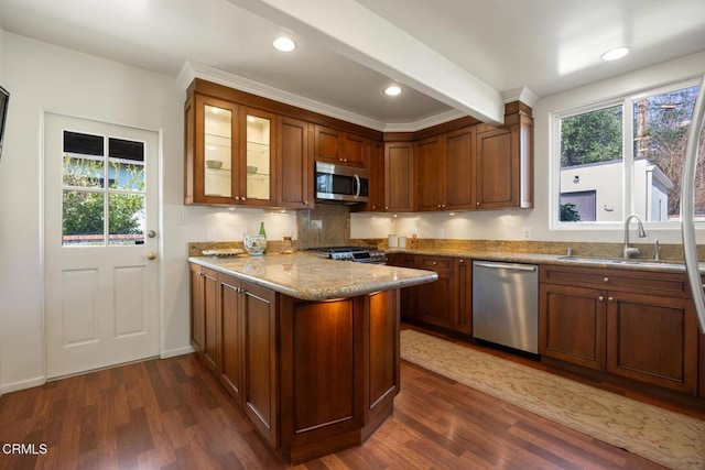 kitchen with sink, appliances with stainless steel finishes, dark hardwood / wood-style floors, light stone countertops, and kitchen peninsula