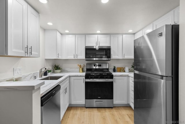 kitchen with sink, light hardwood / wood-style floors, white cabinets, and appliances with stainless steel finishes