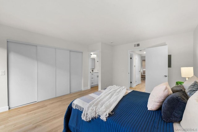 bedroom with ensuite bathroom, a closet, and light wood-type flooring