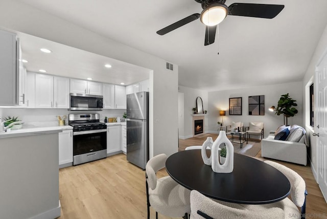 kitchen featuring ceiling fan, appliances with stainless steel finishes, light wood-type flooring, and white cabinets