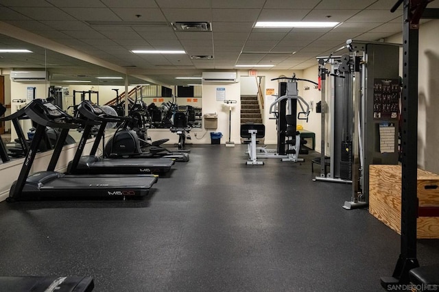 exercise room featuring a paneled ceiling and an AC wall unit