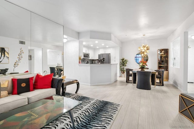 living room featuring an inviting chandelier and light wood-type flooring