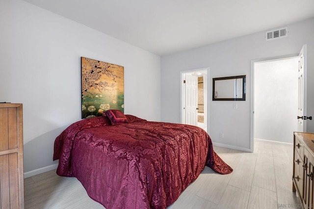 bedroom with connected bathroom and light hardwood / wood-style flooring