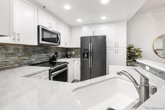 kitchen featuring appliances with stainless steel finishes, sink, white cabinets, backsplash, and light stone countertops