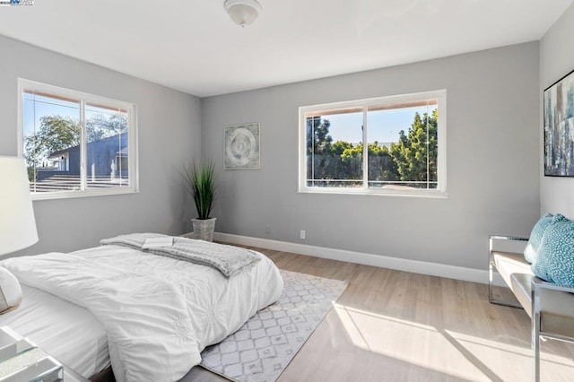 bedroom with multiple windows and light wood-type flooring