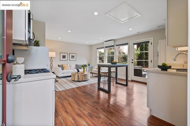 kitchen featuring hardwood / wood-style floors, an AC wall unit, sink, and white fridge