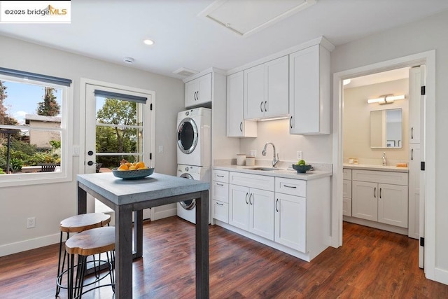 kitchen with white cabinetry, sink, and stacked washing maching and dryer