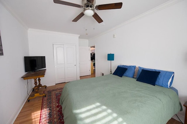 bedroom featuring hardwood / wood-style flooring, ceiling fan, crown molding, and a closet