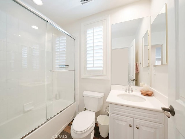 full bathroom featuring vanity, combined bath / shower with glass door, and toilet