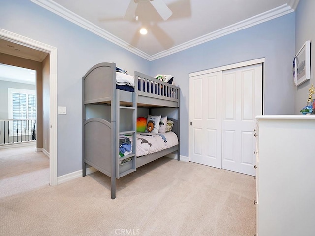 carpeted bedroom with ornamental molding, ceiling fan, and a closet