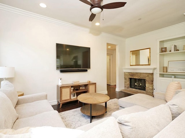 living room featuring dark wood-type flooring, ceiling fan, ornamental molding, and a fireplace