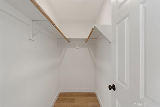 walk in closet with light hardwood / wood-style flooring