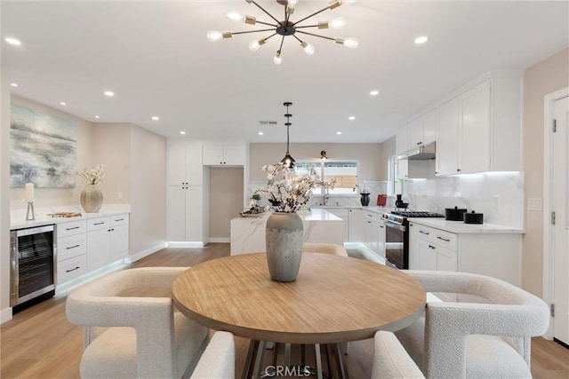 kitchen with wine cooler, white cabinetry, a chandelier, hanging light fixtures, and stainless steel range with gas cooktop