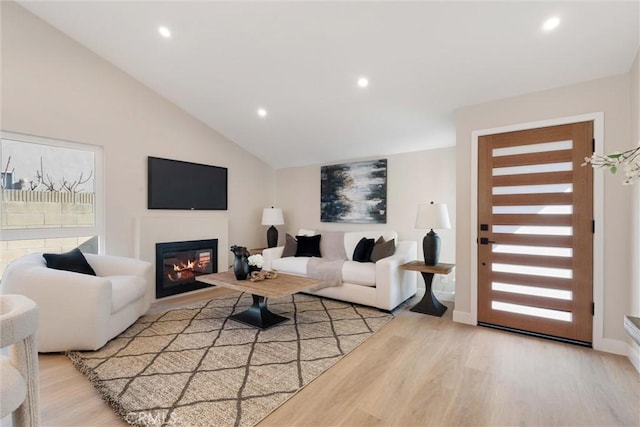 living room with vaulted ceiling, a healthy amount of sunlight, and light wood-type flooring