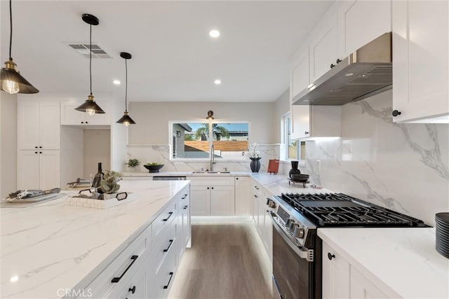 kitchen featuring gas range, hanging light fixtures, and white cabinets