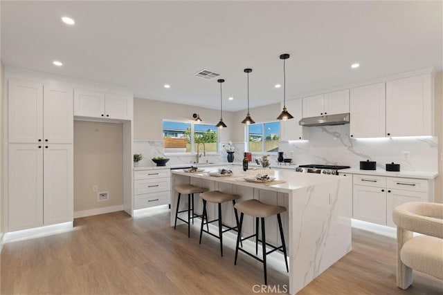 kitchen featuring white cabinetry, pendant lighting, light hardwood / wood-style floors, and a center island