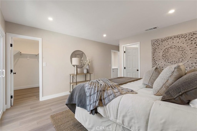 bedroom featuring a walk in closet and light hardwood / wood-style floors