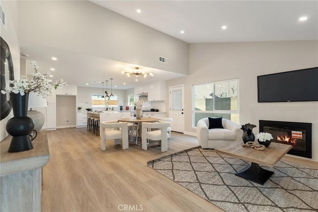 living room with high vaulted ceiling and light wood-type flooring