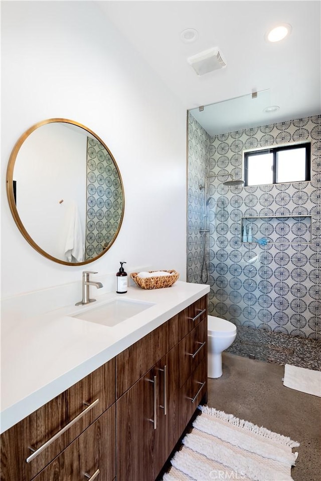 bathroom featuring tiled shower, vanity, and toilet