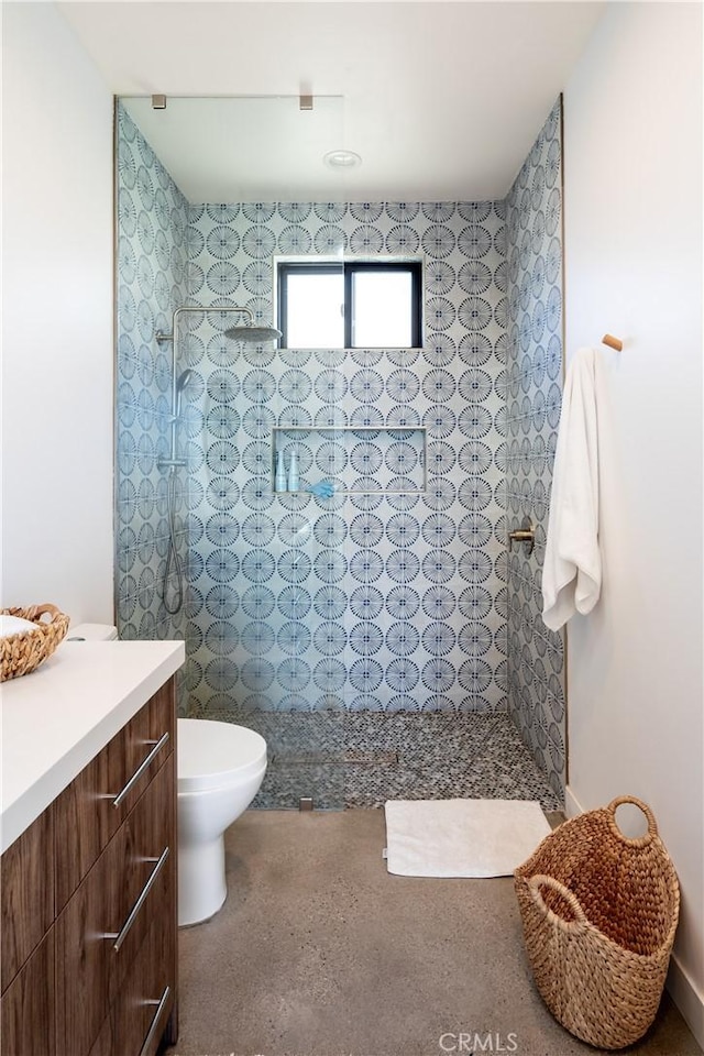 bathroom with vanity, toilet, and a tile shower