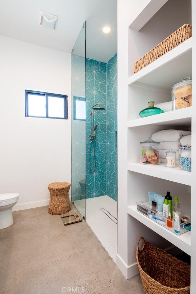 bathroom with toilet, a tile shower, and built in shelves