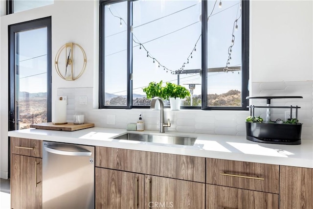 kitchen featuring stainless steel dishwasher, sink, and decorative backsplash