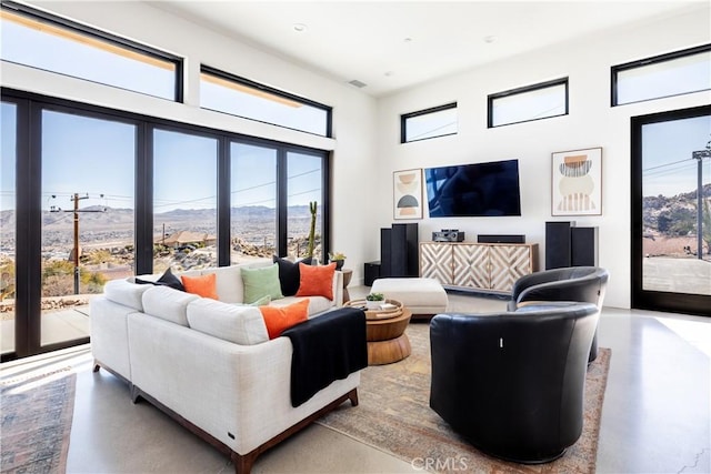 living room with a towering ceiling and concrete flooring